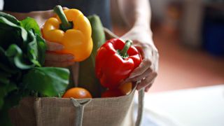 woman taking a yellow and red bell pepper from shopping bag