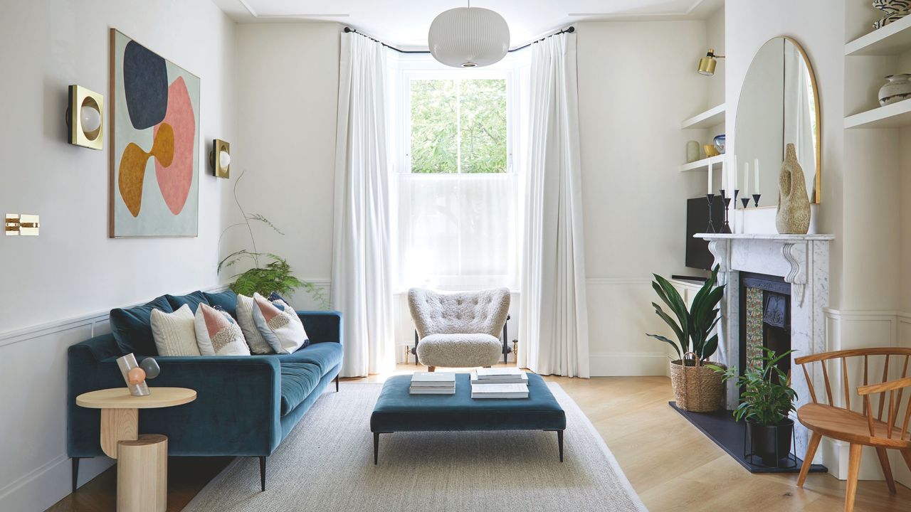 White living room with white curtains, a white accent chair and a blue sofa with matching coffee table