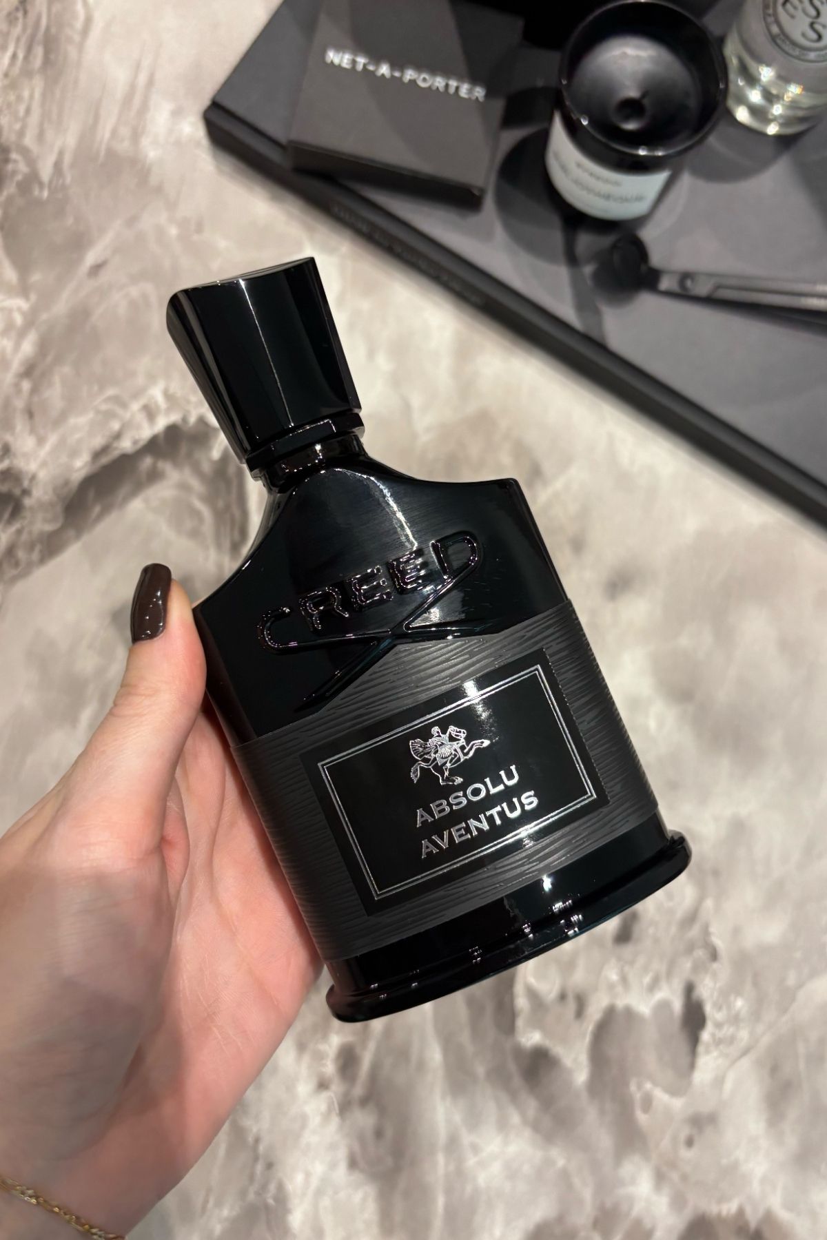 Deputy beauty editor Grace Lindsay holding a bottle of Creed Absolu Aventus