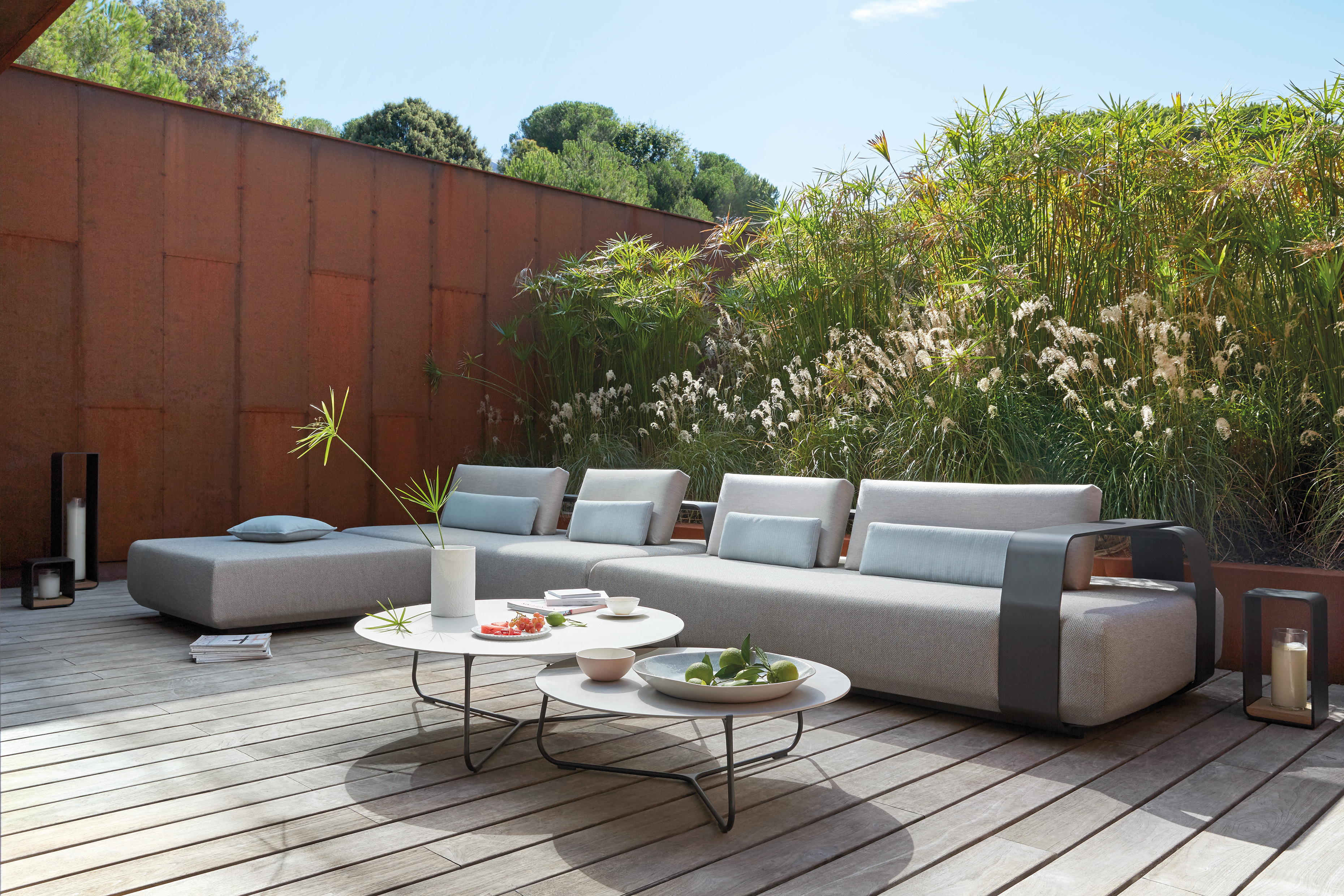 Large cushioned sofa on light colored decking area with round low table