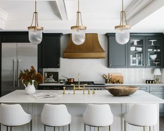 Grey and white kitchen ideas with a white island, dark grey cupboards and a brass hood and pendant light fittings