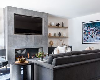 Modern living room with dark gray sofa, fireplace, alcove shelving