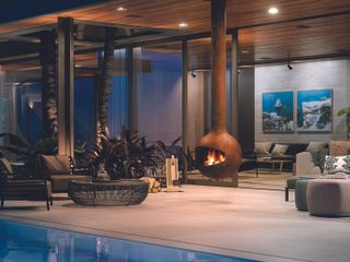 suspended outdoor fireplace hanging by a pool in a luxe urban backyard