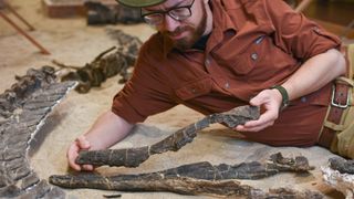 A man poses with fossils from a new species of plesiosaur.