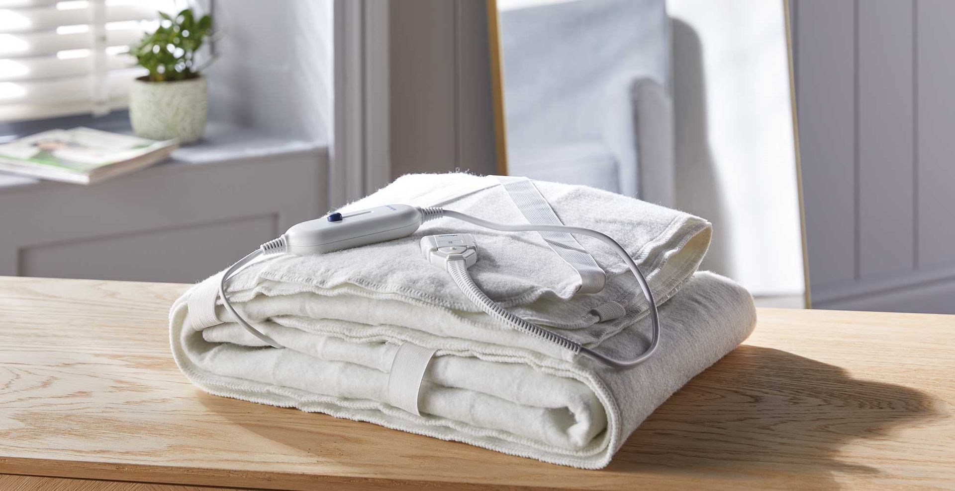 Folded Aldi electric blanket on a wooden sideboard in a bedroom