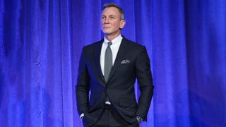 Daniel Craig in front of blue curtain wearing a MoonSwatch