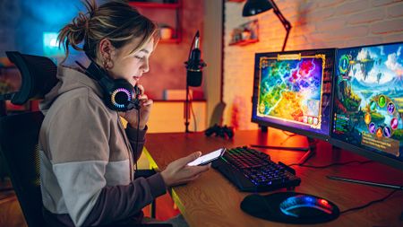 A female gaming influencer records gameplay at home using professional streaming equipment and a stylish gaming desk.