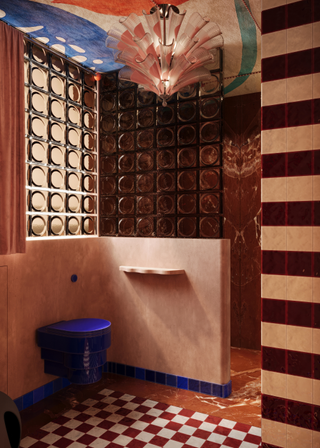 a playful bathroom with a painted ceiling, a striped wall, checkerboard flooring, glass block shower wall and a blue toilet