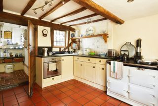 cream kitchen in cottage kitchen with terracotta tiles and beamed ceilings