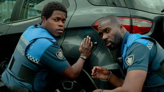 L-R: Ramon and Jack crouch beside a car in a scene from Netflix's "Almost Cops"