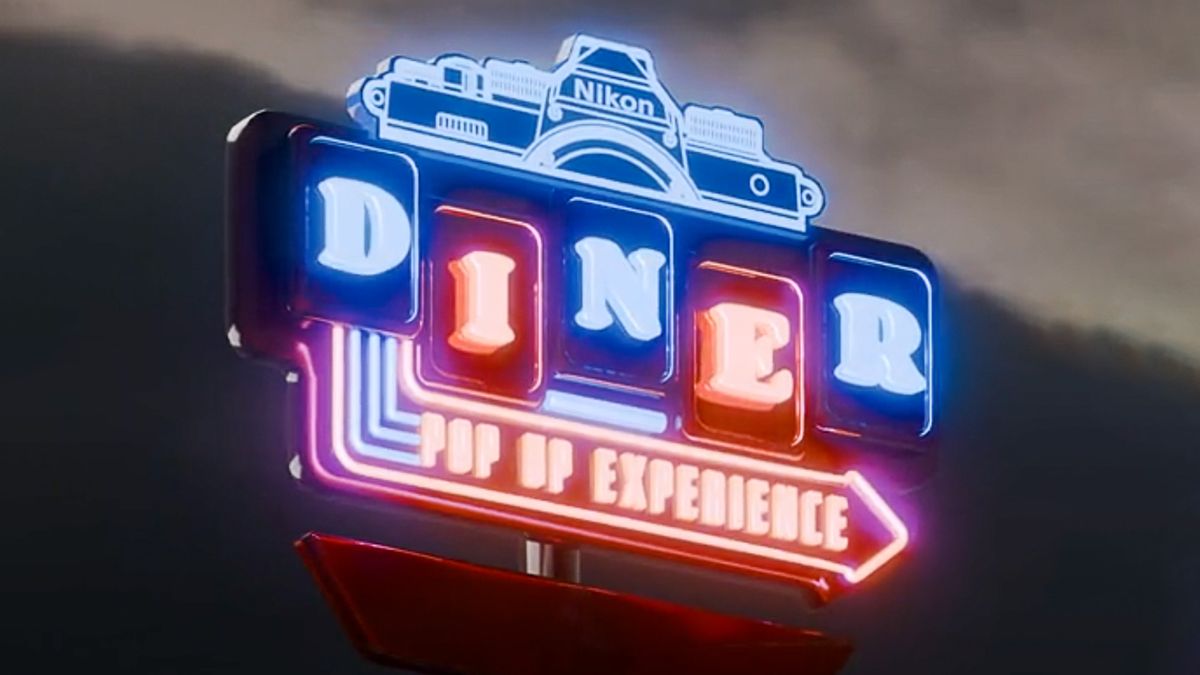 Retro neon Nikon Diner Pop-up Experience sign on a cloudy background 