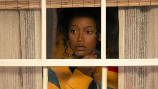 Keke Palmer looking through window and curtains in Peacock's The Burbs series