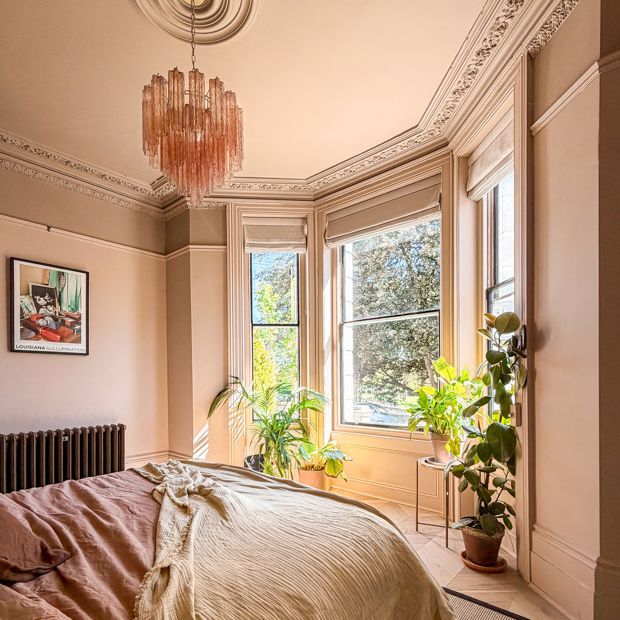 Neutral bedroom with bay window area filled with houseplants