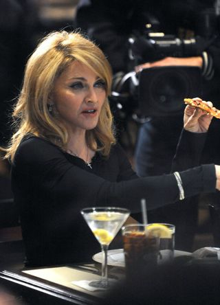 Madonna sitting at a table with a cocktail glass