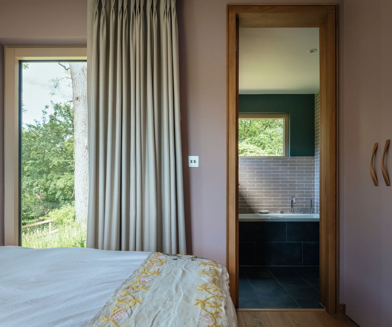 bedroom with large floor to ceiling window and wooden pocket door leading into bathroom