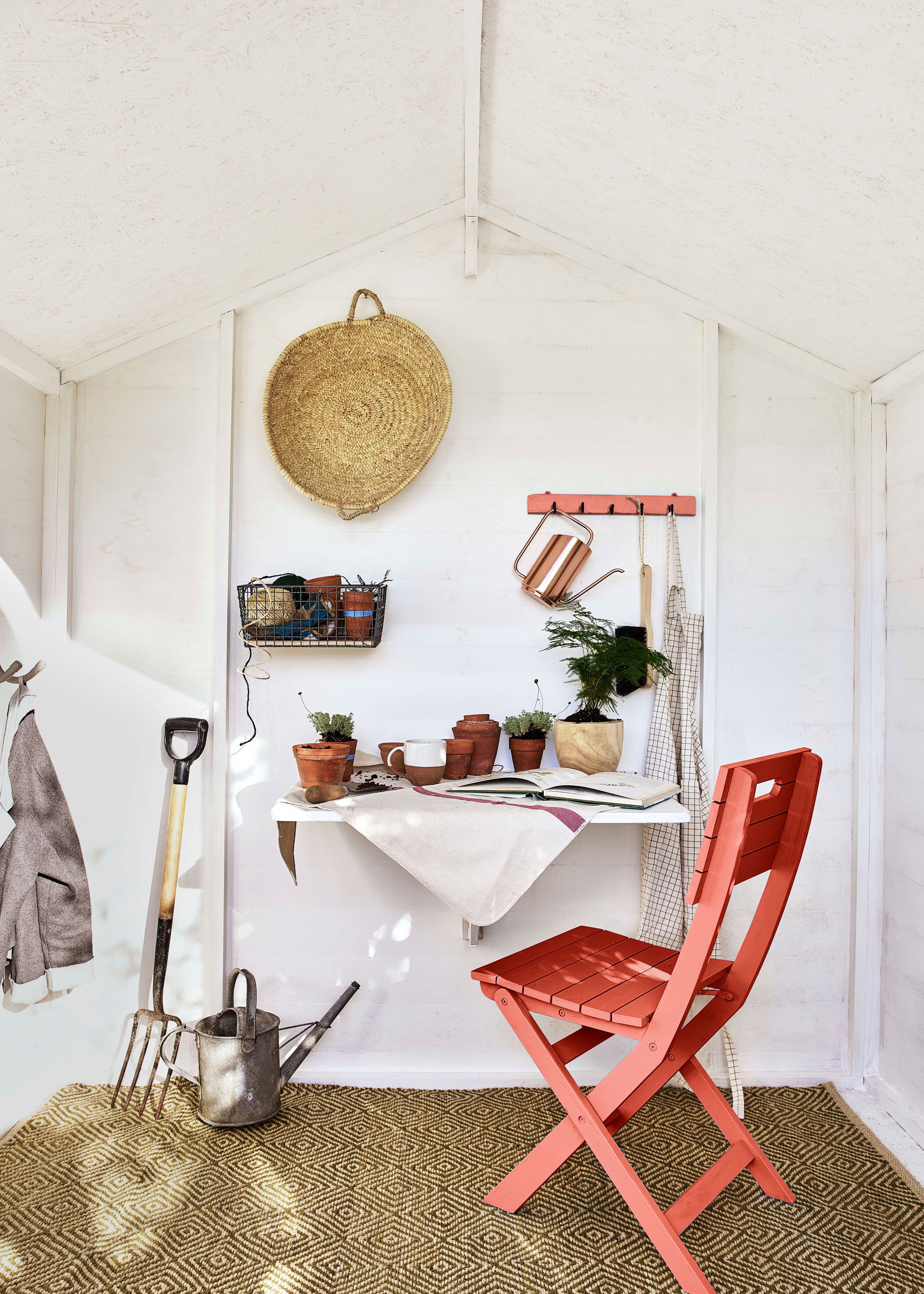 interior of garden shed with rush mat, garden chair and garden equiplent such as fork and watering can