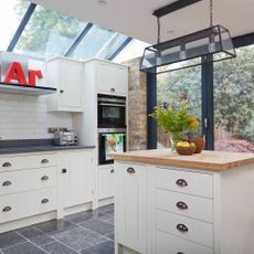 kitchen with white cabinets wooden counter roof window and glass door 