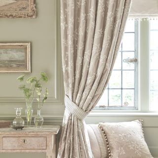 living room with patterned curtains paired with a cream blind with pompom trim