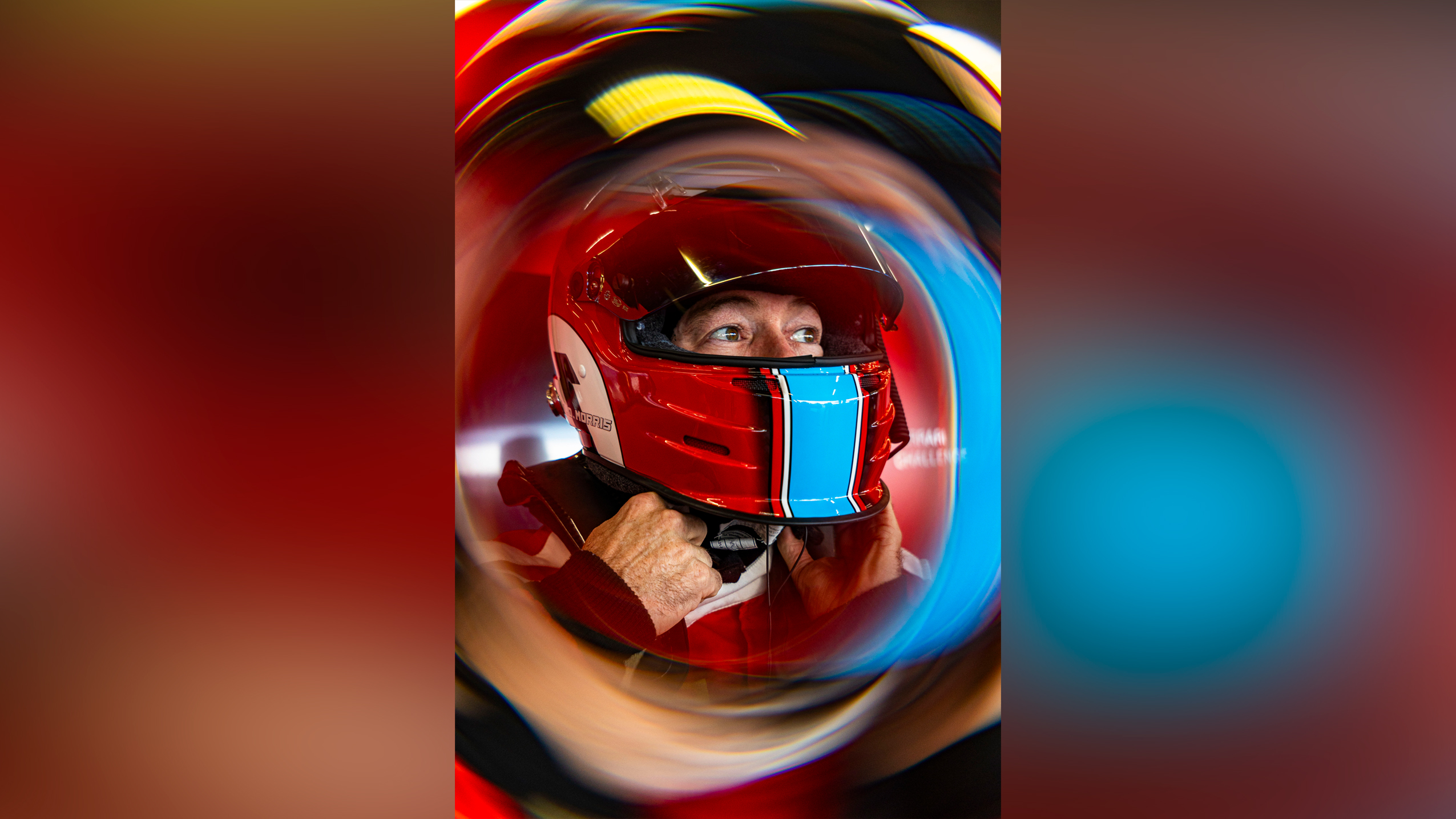 Race car driver in a red helmet fastening the chin strap, with a swirling motion blur effect around the image
