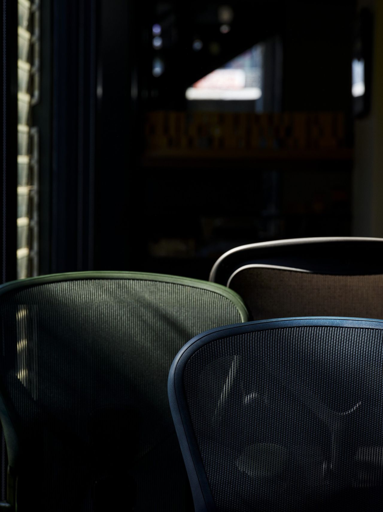 Close-up of the Herman Miller in blue and green in a dark room.