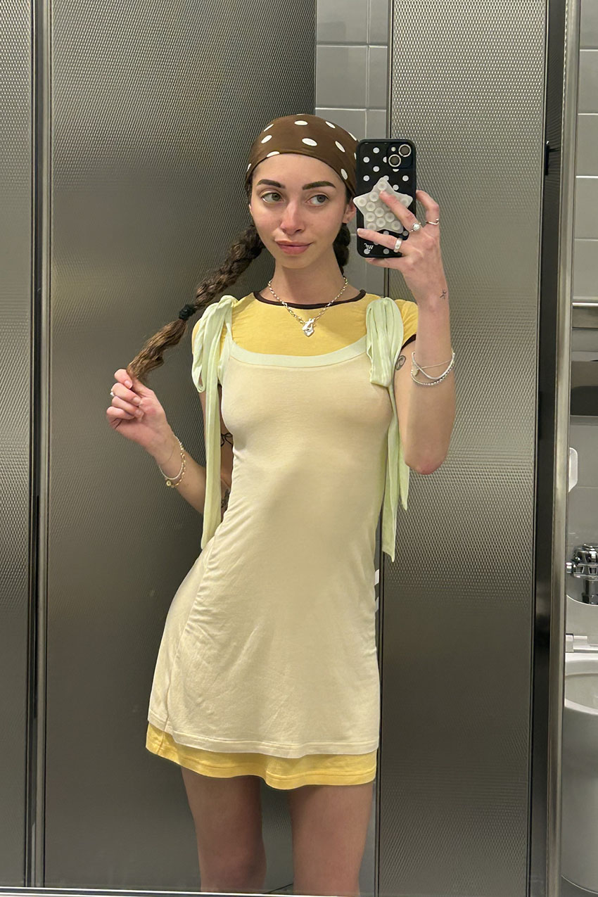 A woman wearing a layered yellow dress and polka dot bandana.