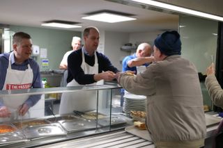 Prince william serving food to a homeless man at a shelter