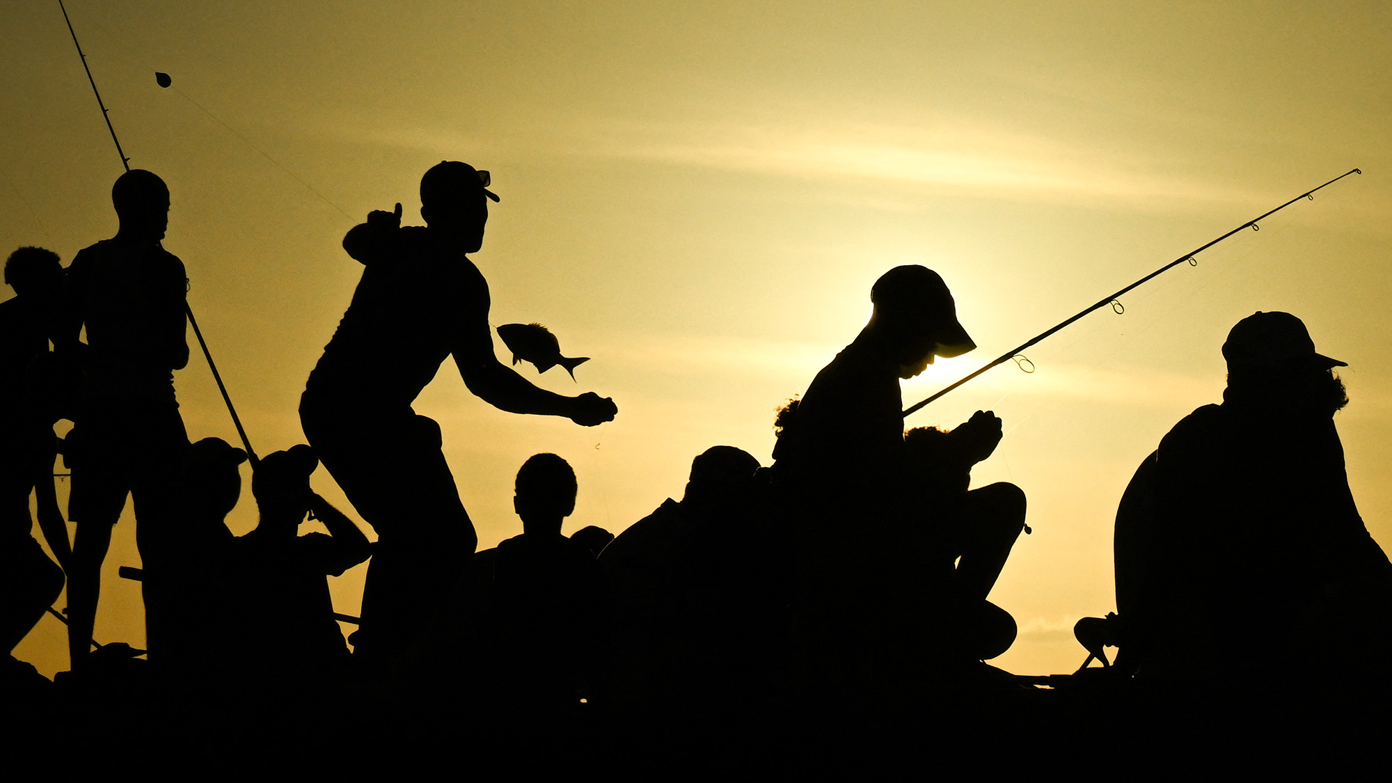 People fish at sunset along the Malecon esplanade in Havana, Cuba