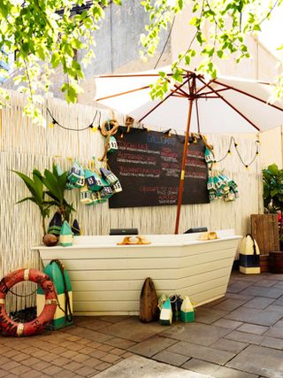 Gilligan's, New York, USA. A boat shaped outdoor decoration against a wooden fence with a white umbrella above it.