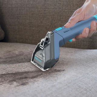 Using the Shark Stainstriker on a dirty grey sofa