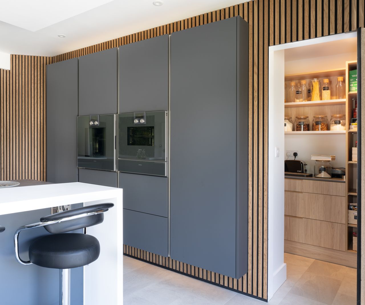 hidden door opened in wood panelling in kitchen revealing utility room behind