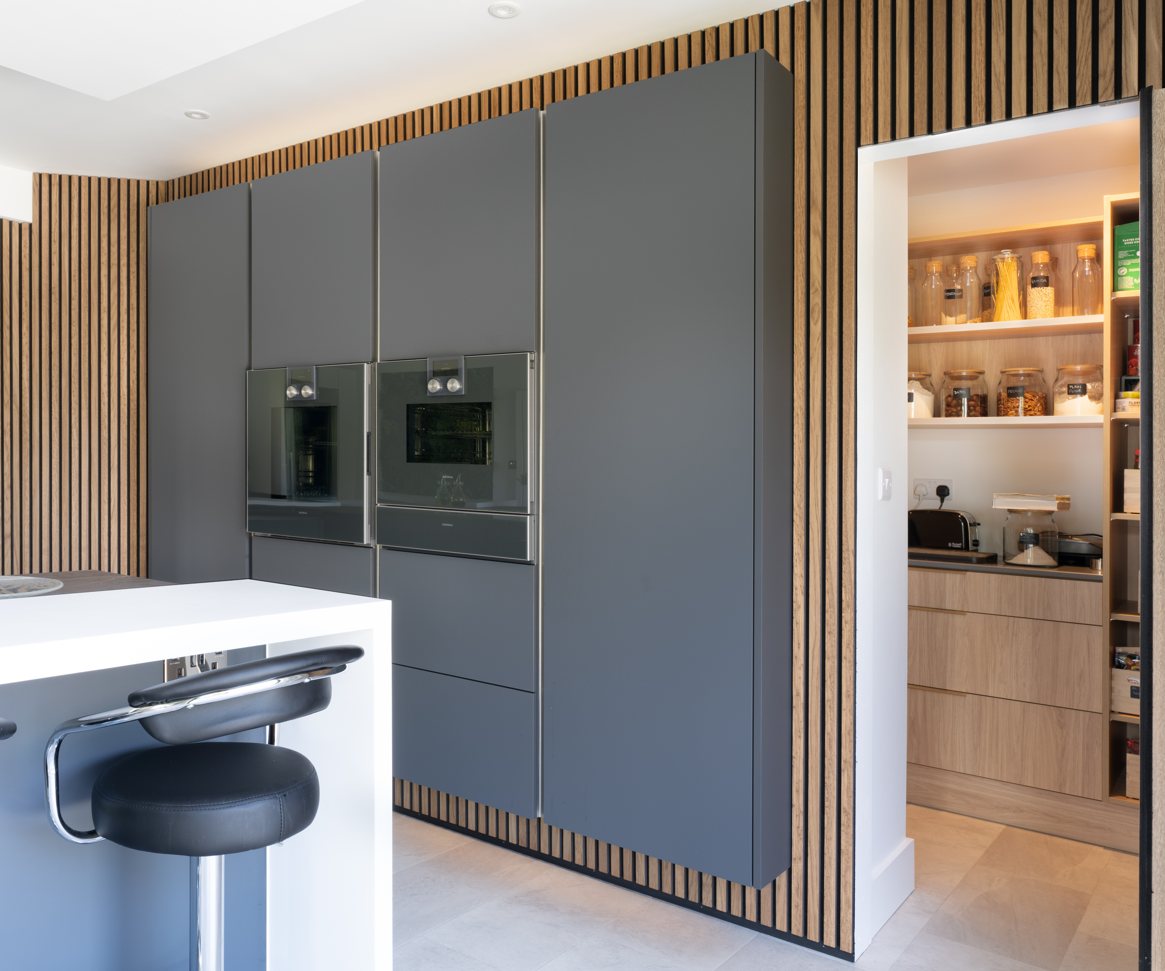 hidden door opened in wood panelling in kitchen revealing utility room behind