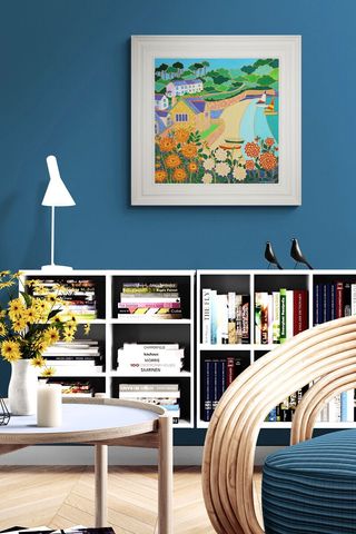 blue living room with shelving, lamp and colourful artwork