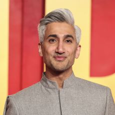 Tan France in front of red and yellow backdrop