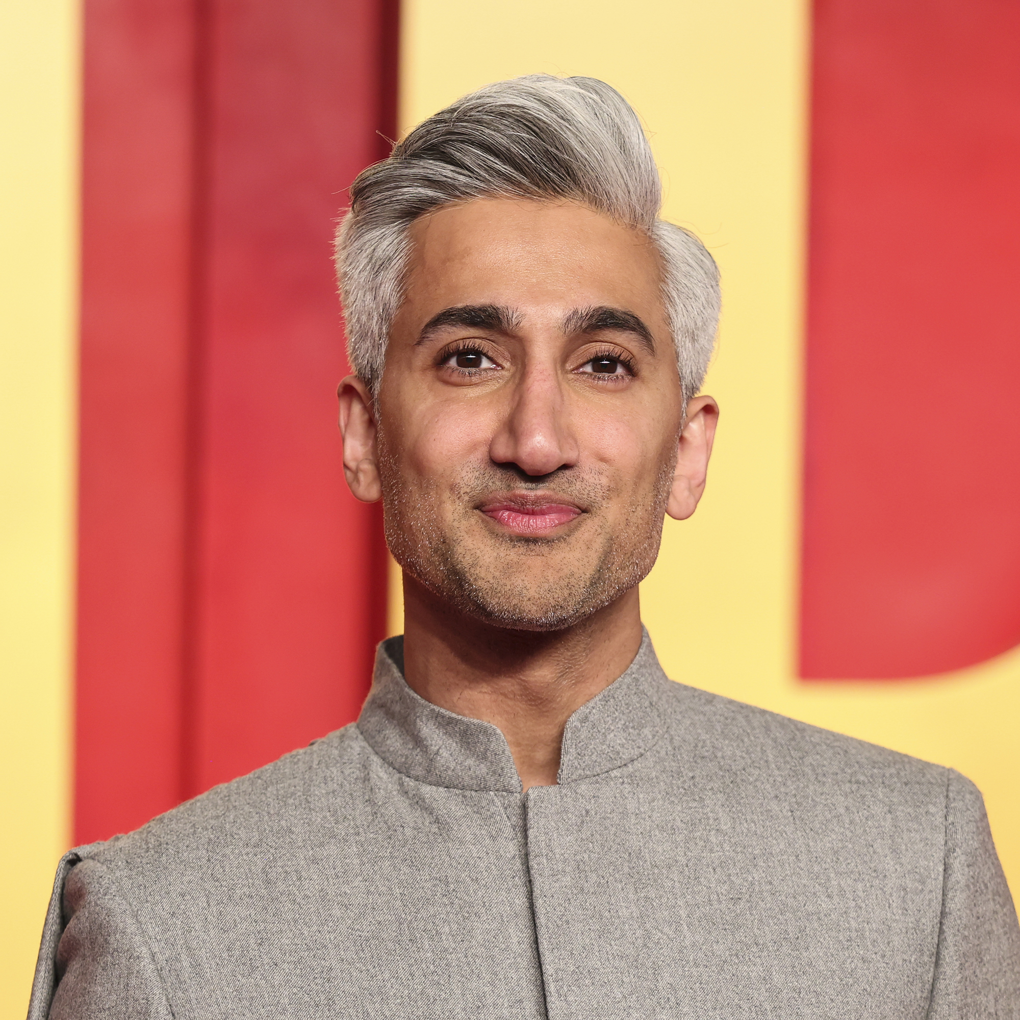 Tan France in front of red and yellow backdrop