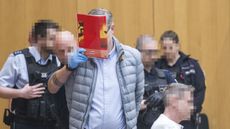A defendant in the Reichsburger trial arrives in court with his face covered with a magazine