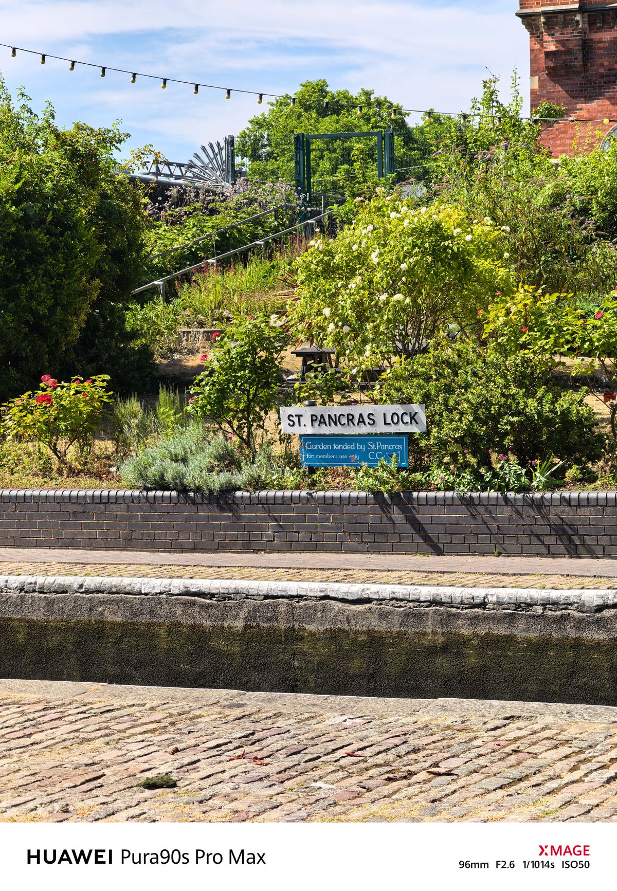 St Pancras Lock sign surrounded by flowers and dense planting in a canal-side garden.