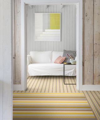 two different types of yellow striped carpet laid in different ways in hallway compared to living room