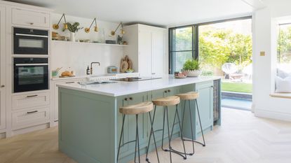 large bright kitchen with pale green kitchen island and cream cabinets 