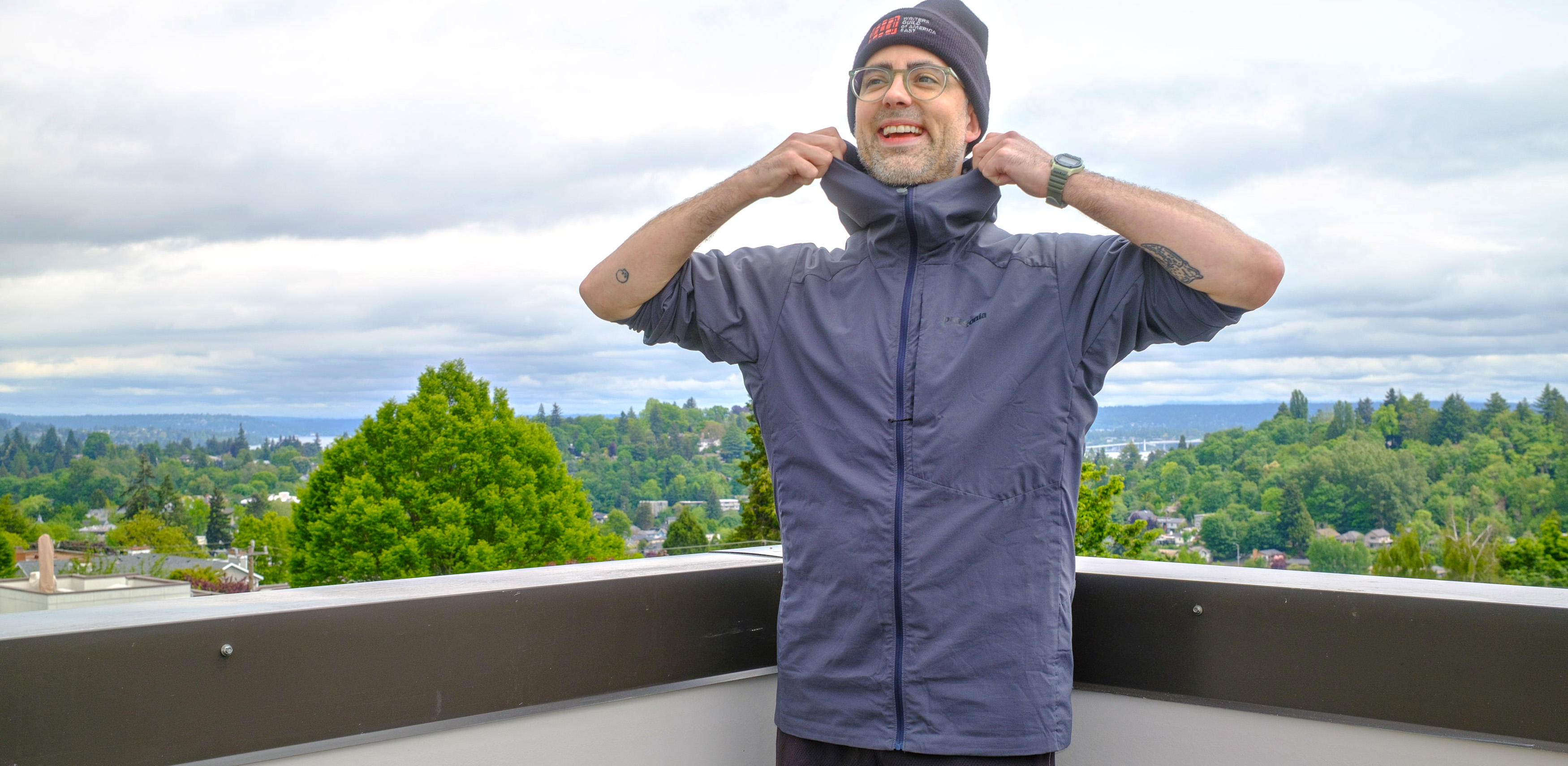 Senior writer Dan Bracaglia wearing the Patagonia Nano-Air Ultralight in grey/blue on the roof of his home in Seattle, Washington with trees and overcast skies in the distance