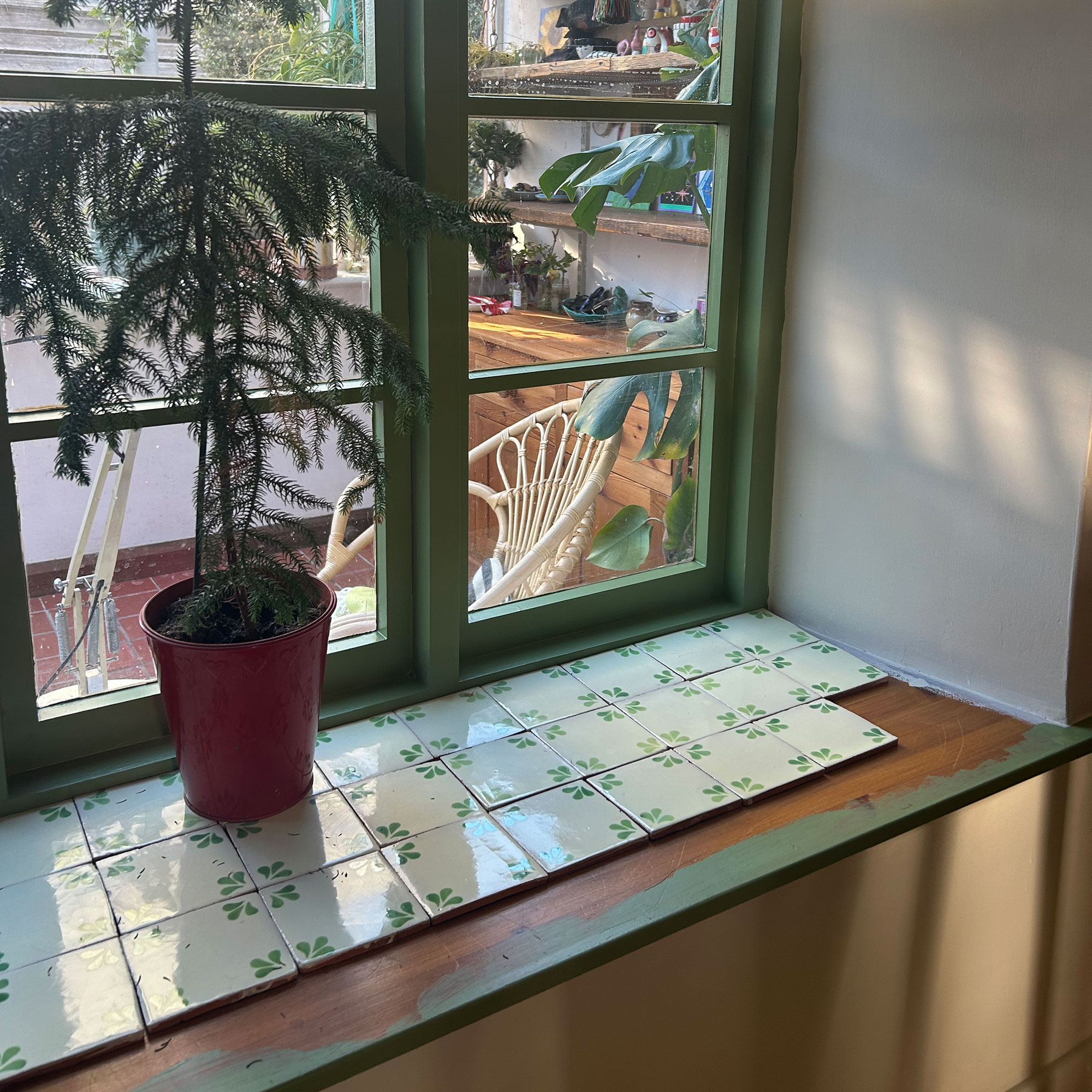 Windowsill being tiled with cream and green tiles