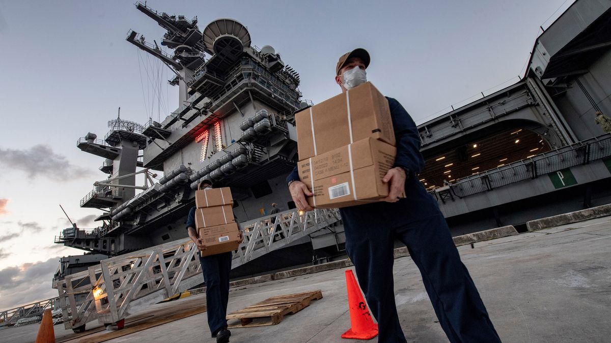 Sailors assigned to the aircraft carrier USS Theodore Roosevelt carry food supply boxes for sailors who either tested negative or are asymptomatic for COVID-19 and are staying at local hotels in Guam on April 7, 2020.