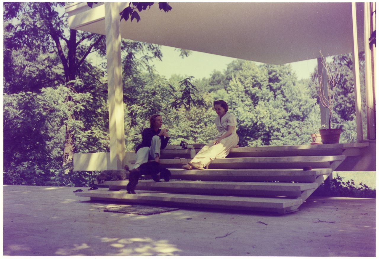 two women with black dog on steps