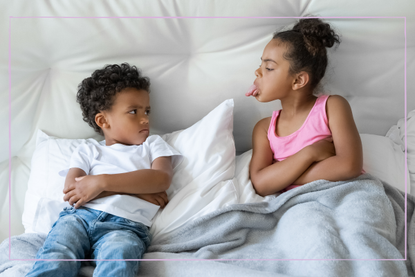 Hermana y hermano afroamericanos, niños pequeños peleándose acostados en la cama
