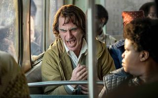 Joaquin Phoenix as Arthur Fleck acting out on a city bus.