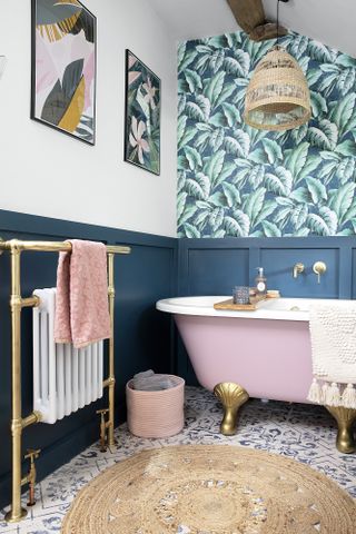 Bathroom with dark blue panelling, palm wallpaper, pink roll top bath and patterned tile floor
