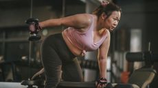 A woman doing a dumbbell workout in a gym