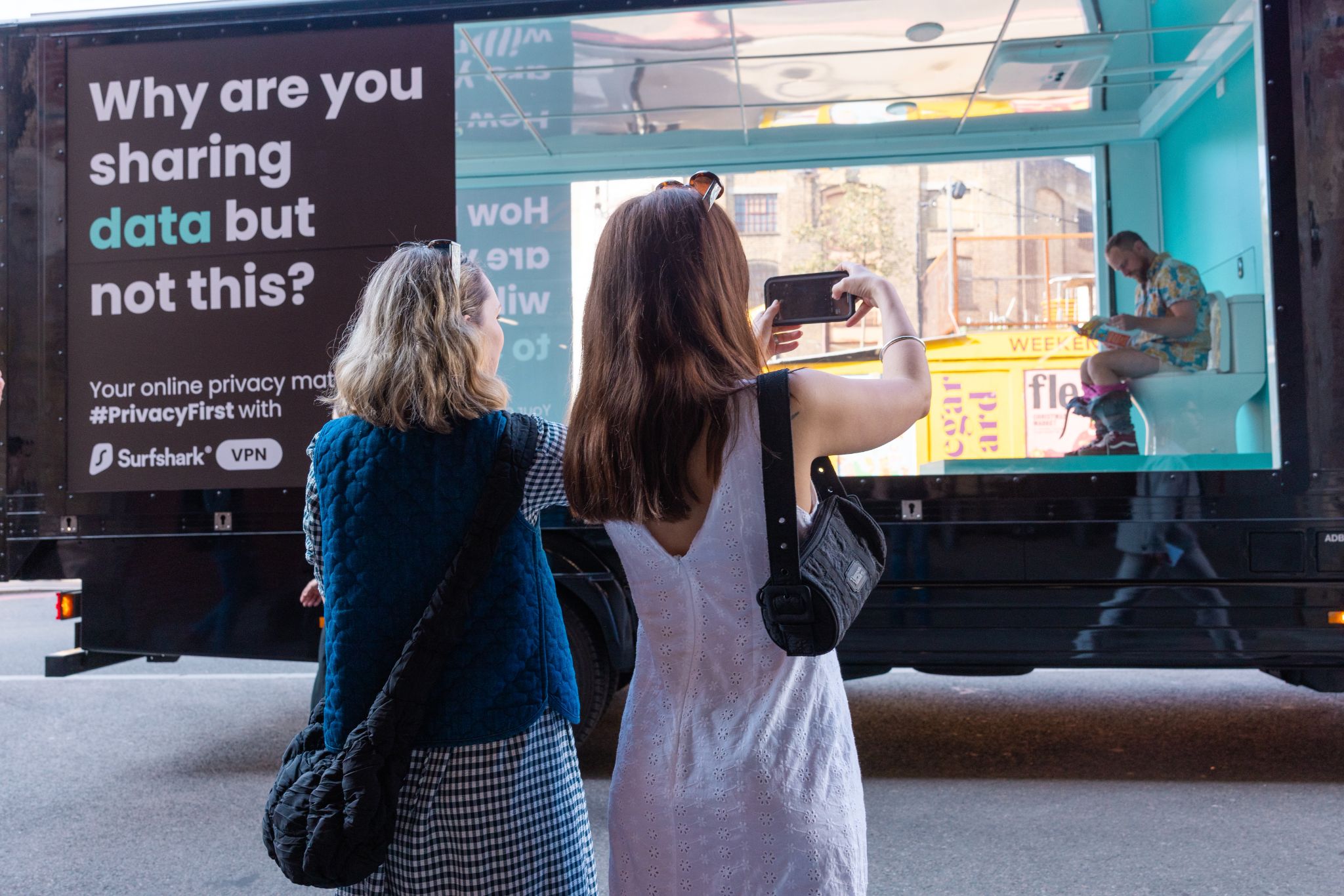 Personas tomando fotografías del camión transparente con baño de Surfshark en Londres el 9 de mayo de 2024
