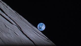 Marmura albastră a Pământului se strecoară peste orizontul lunar în timpul unei eclipse de soare.  Umbra neagră a lunii poate fi văzută peste Australia.