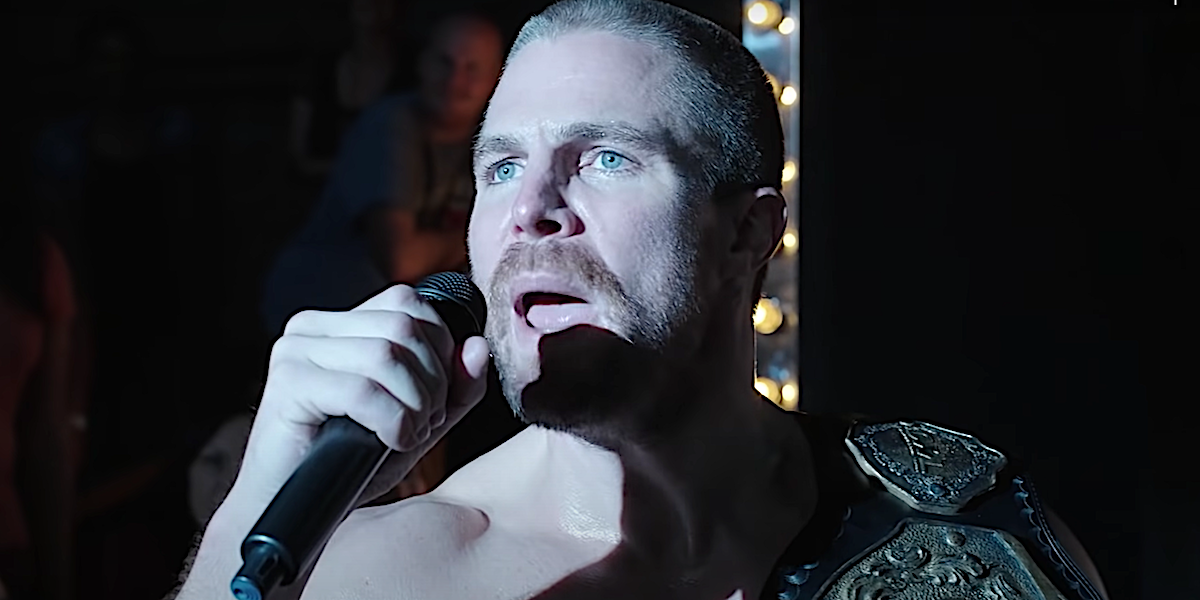 Stephen Amell talks into a microphone in the wrestling ring in Heels.