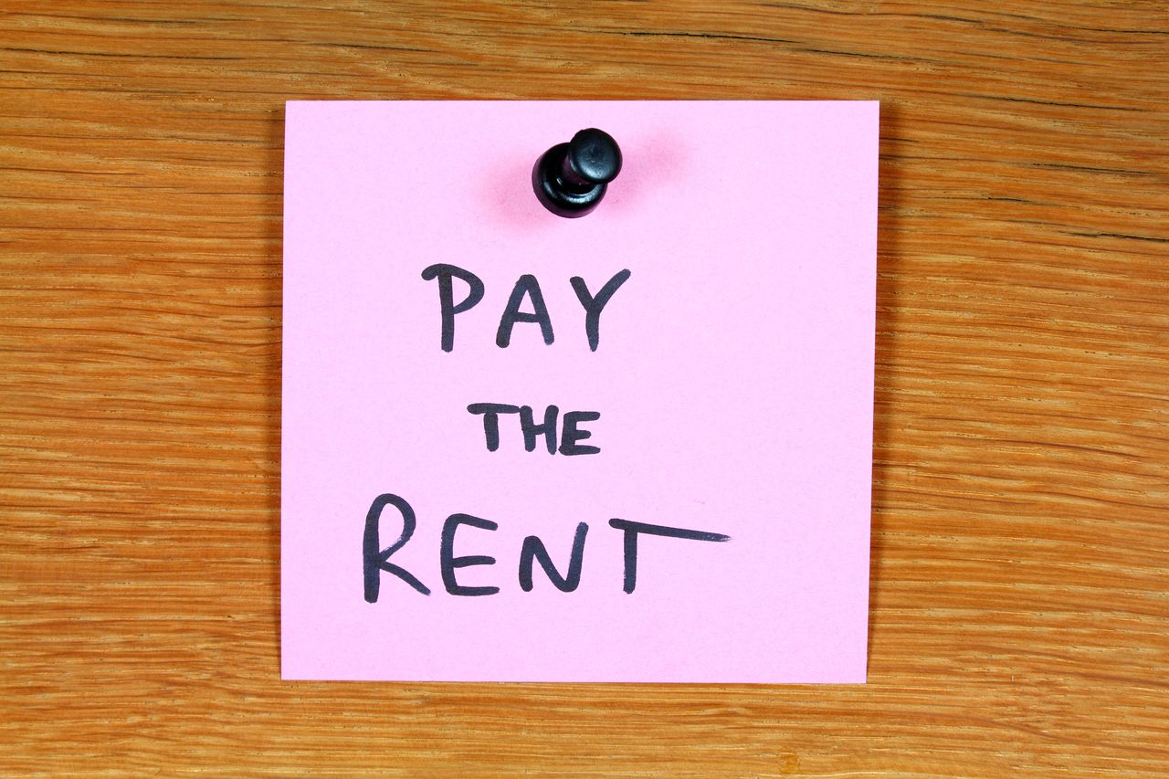 image of a pink post it note with pay the rent written on it